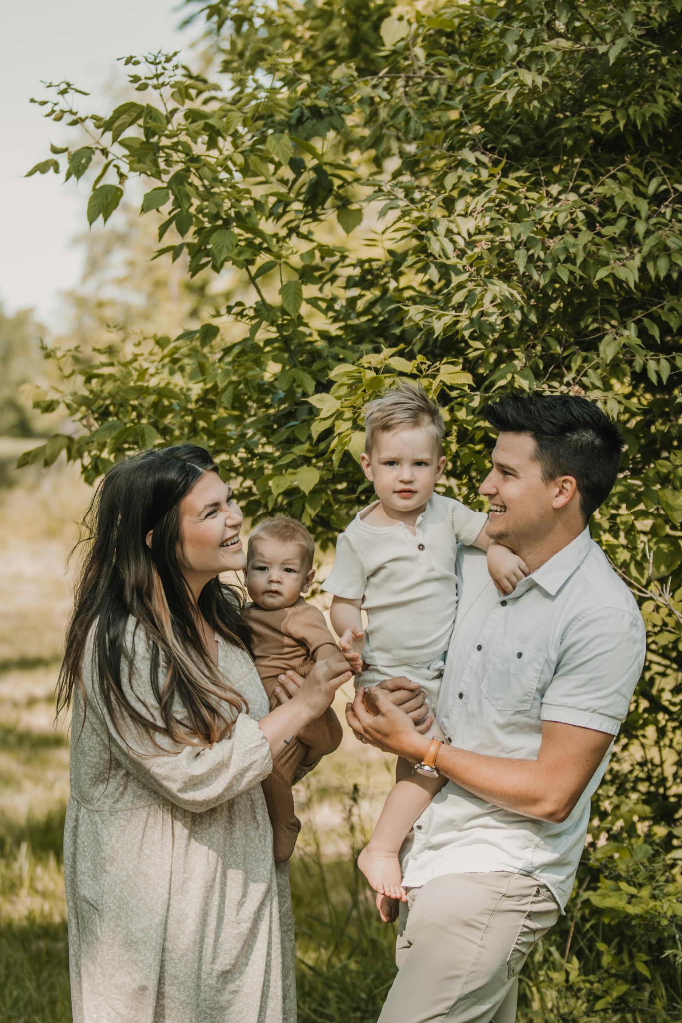 A joyful family of four enjoying a sunny day amidst lush greenery in Kansas City.