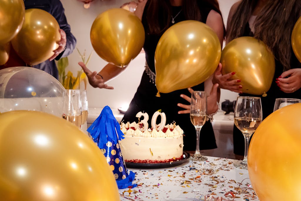 A lively 30th birthday party featuring friends, golden balloons, and a festive cake.